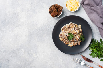 Stewed mushrooms champignons in sauce with sour cream and cheese parsley on a plate. Copy space.