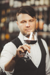 Male sommelier tasting red wine at cellar.