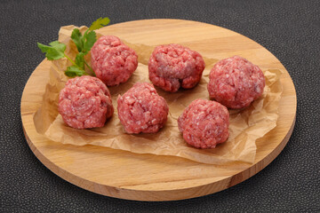 Raw meatball over wooden background