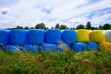 Obraz premium Resmo, Oland, Sweden Yellow and blue hay bales stacked in a field.