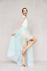 Fototapeta na wymiar Beautiful young woman plays with hem of transparent tulle dresses with lace
