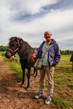 Helgenaes, Denmark  A man stads with a horse ready for horsebackriding