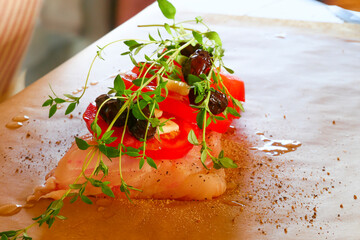 The kitchen preparation of white fish with olives, tomatoes, and garlic for the oven.