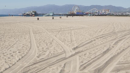Ocean waves and sandy california beach, classic ferris wheel in amusement park on pier in Santa Monica pacific ocean resort. Summertime iconic view, symbol of Los Angeles, CA USA. Travel concept