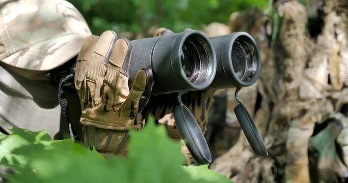 The soldier looks through binoculars. Slow motion.