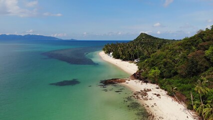 Green jungle and stony beach near sea. Tropical rainforest and rocks near calm blue sea on white sandy shore of Koh Samui paradise island, Thailand. Dream beach drone view. Relax and holiday concept.
