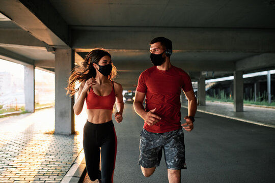 Couple running in an urban environment wearing protective masks