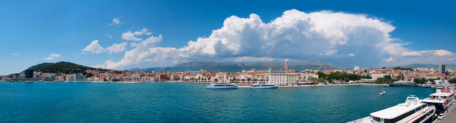 Fototapeta na wymiar Split city in Dalmatia, Croatia on a bright day with clouds. Panoramic image of harbor with passenger ships.