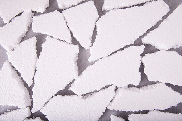 Pieces of white expanded polystyrene close-up on a gray background, flat layout