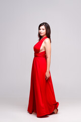 Beautiful woman in red dress in studio on gray background