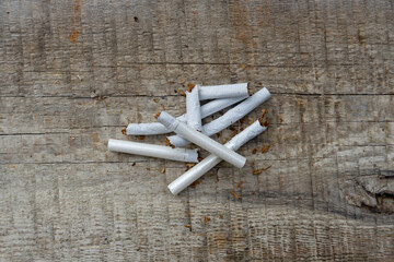Broken cigarettes lie on a wooden surface. Cigarettes are addictive. Campaign to reduce smoking on...