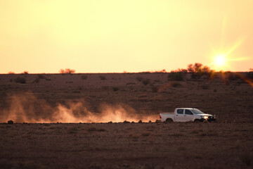 car on a dusty unsealed road in sunset light mood