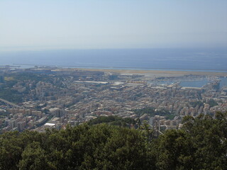 Genova, Italy – 07/30/2020: Beautiful scenic aerial view of the city, port, dam, sea, Cristoforo Colombo airport runway, containers shipping terminal, Pra, Voltri, and Sestri promontory from Monte Gaz