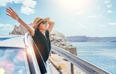 Cheerful Woman portrait enjoying the seaside road trip. Dressed a black dress, straw hat and...
