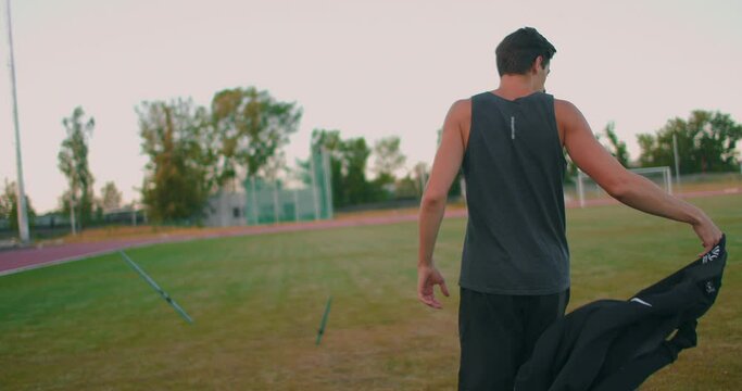 Slow motion: a Male athlete at the stadium concentrates and prepares to do a javelin throw. Attitude and serious expression. Goes around collecting spears. Training of a javelin thrower