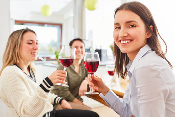 Group of women as friends talk over glass of red wine