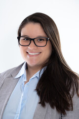 Business woman studio portrait. She is wearing eyeglasses, gray suit and blue shirt. She is smiling to the camera.