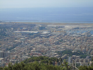 Genova, Italy – 07/30/2020: Beautiful scenic aerial view of the city, port, dam, sea, Cristoforo Colombo airport runway, containers shipping terminal, Pra, Voltri, and Sestri promontory from Monte Gaz