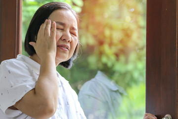 Alone old woman holding head by hand cause of headache, elder care or healthy concept