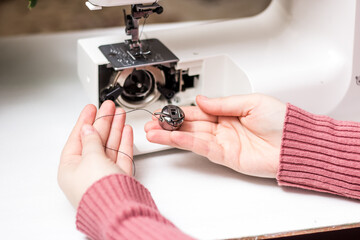 The girl is threading the needle of a sewing machine. Close plan. White sewing machine. Sewing content.