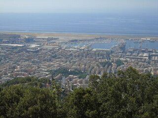 Genova, Italy – 07/30/2020: Beautiful scenic aerial view of the city, port, dam, sea, Cristoforo Colombo airport runway, containers shipping terminal, Pra, Voltri, and Sestri promontory from Monte Gaz