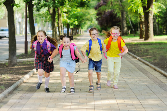 a group of school children in colored clothes with school bags and backpacks run to school smiling. School year, back to school, knowledge day.