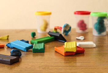 Strips of multi-colored plasticine are scattered on the table against the background of cans of air plasticine, close-up