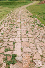 An old stone medieval road, in the green grass. Background, a copy space.