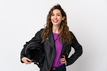 Young caucasian woman holding a motorcycle helmet posing with arms at hip and smiling