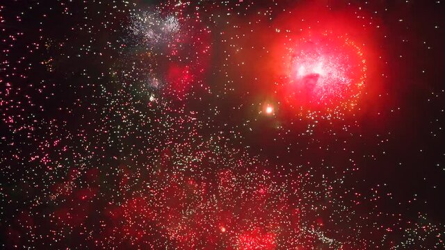 Culminating Extravaganza of Fireworks. Massive explosions of fireworks illuminate the night sky with bright, slow flashes. Filmed at a speed of 240fps