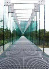 A perspective view of a metal and glass corridor located on the roof of a museum in Poland.