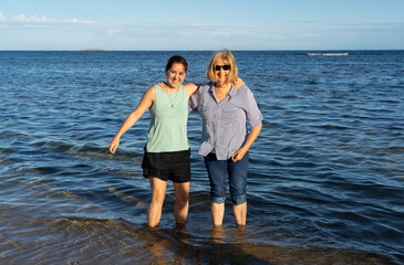 Happy active senior and adult daughter having fun together in summer beach on sunny day