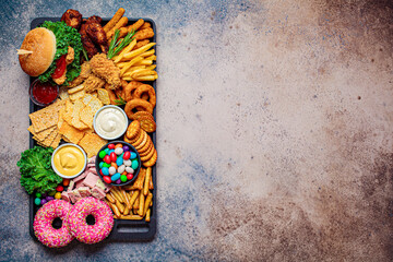 Fast food platter. Junk food concept. Unhealthy food for the heart, teeth, skin, figure, top view.