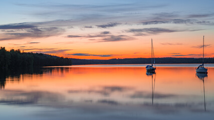 Fototapeta na wymiar Long exposure image of boat on the calm lake during sunset or sunrise