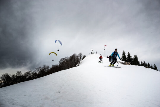 People Skiing And Paragliding On Snow Covered Landscape