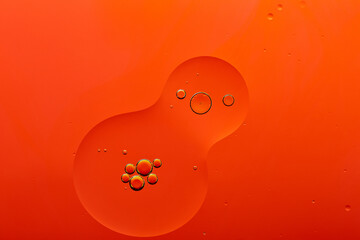 Current collection of brilliant backgrounds for your design. Close-up shot of golden oil bubbles in the water spill on orange surface.