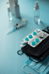 protective medical face mask and disinfectant alcohol sanitizer spray to prevent coronavirus disease. products to protect from germs when on the go. blue background for text