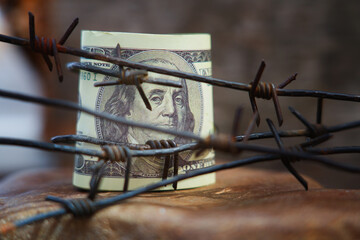 Economic warfare, sanctions and embargo busting concept Barbed wire against US Dollar bill. Horizontal image.