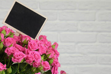 Bouquet of pink roses on a white brick wall background with copy space. The concept of flowers, floristry, holiday. Mock up