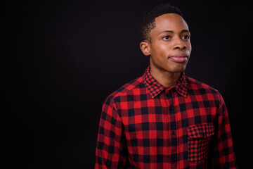 Young handsome African hipster man against black background