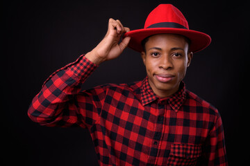 Young handsome African hipster man against black background