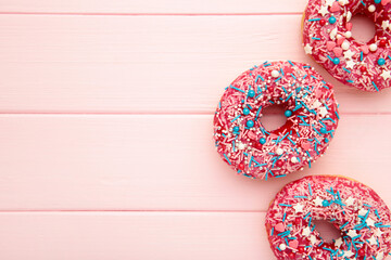 Donuts with icing on pink wooden background. Sweet donuts. Glazed donut.
