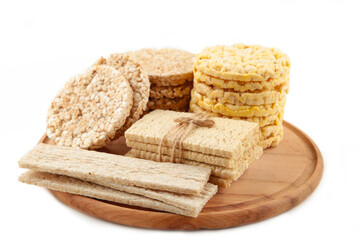 Various types of healthy whole grain crispbreads on cutting board isolated on white background.