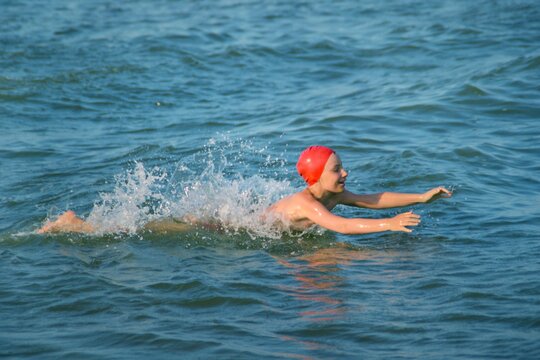 The Child Happily Swims On The Sea Waves