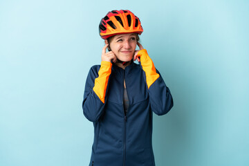 Young cyclist woman isolated on blue background frustrated and covering ears