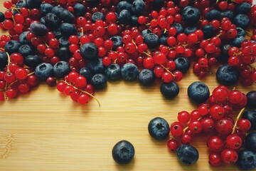 Appetizing fresh red currant and blueberry berries on wooden board