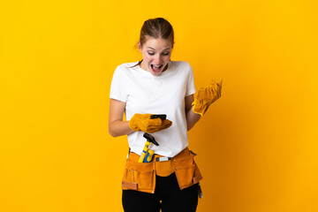 Young electrician woman isolated on yellow background surprised and sending a message