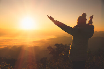 Copy space of silhouette woman raise hand up on top of mountain and sunset  background. Freedom feel good and travel adventure holiday concept. Religious beliefs