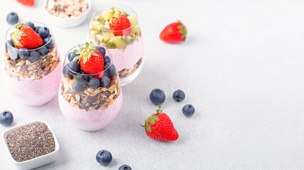 Obraz na płótnie Canvas Superfoods layered pudding with granola, blueberry and strawberry in glasses. Yogurt with chia seeds, berries, kiwi and muesli for healthy breakfast, copy space. Perfect for summer snack or dessert