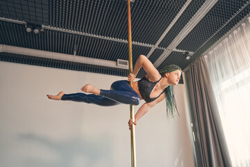 Attractive young woman dancing on pylon in studio